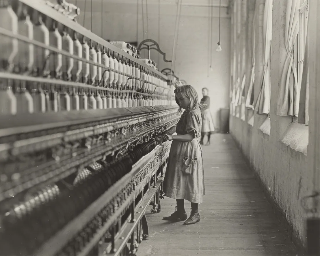 A young girl working at a textile mill in early 20th-century America, part of Lewis Hine's child labor documentation. before enhancement and upscaling