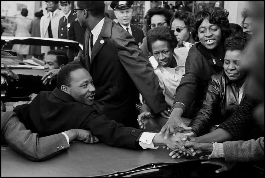 Dr. Martin Luther King Jr. reaching out and shaking hands with individuals in a crowd during the Civil Rights Movement. before enhancement and upscaling