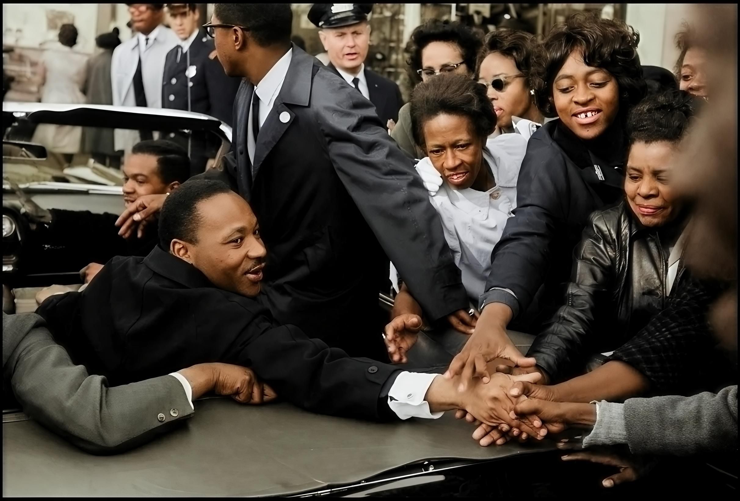 Dr. Martin Luther King Jr. reaching out and shaking hands with individuals in a crowd during the Civil Rights Movement. after enhancement and upscaling