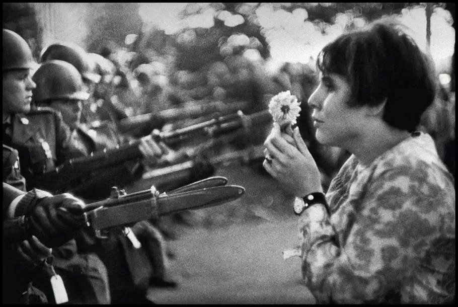 A young woman offering a chrysanthemum to armed National Guardsmen during an anti-Vietnam War protest. before enhancement and upscaling