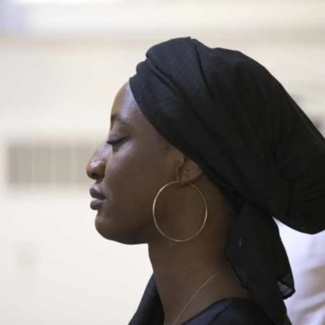 Profile portrait of a woman in a headwrap upscaled with AI, with skin and fabric texture resolved and identity preserved before enhancement and upscaling