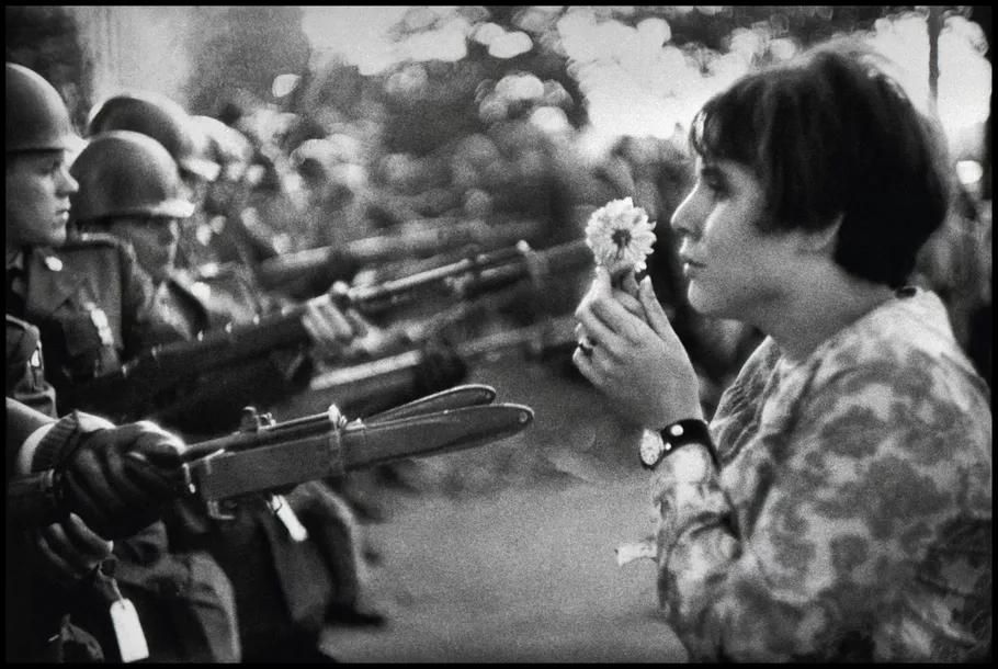 A young woman offering a chrysanthemum to armed National Guardsmen during an anti-Vietnam War protest. before enhancement and upscaling