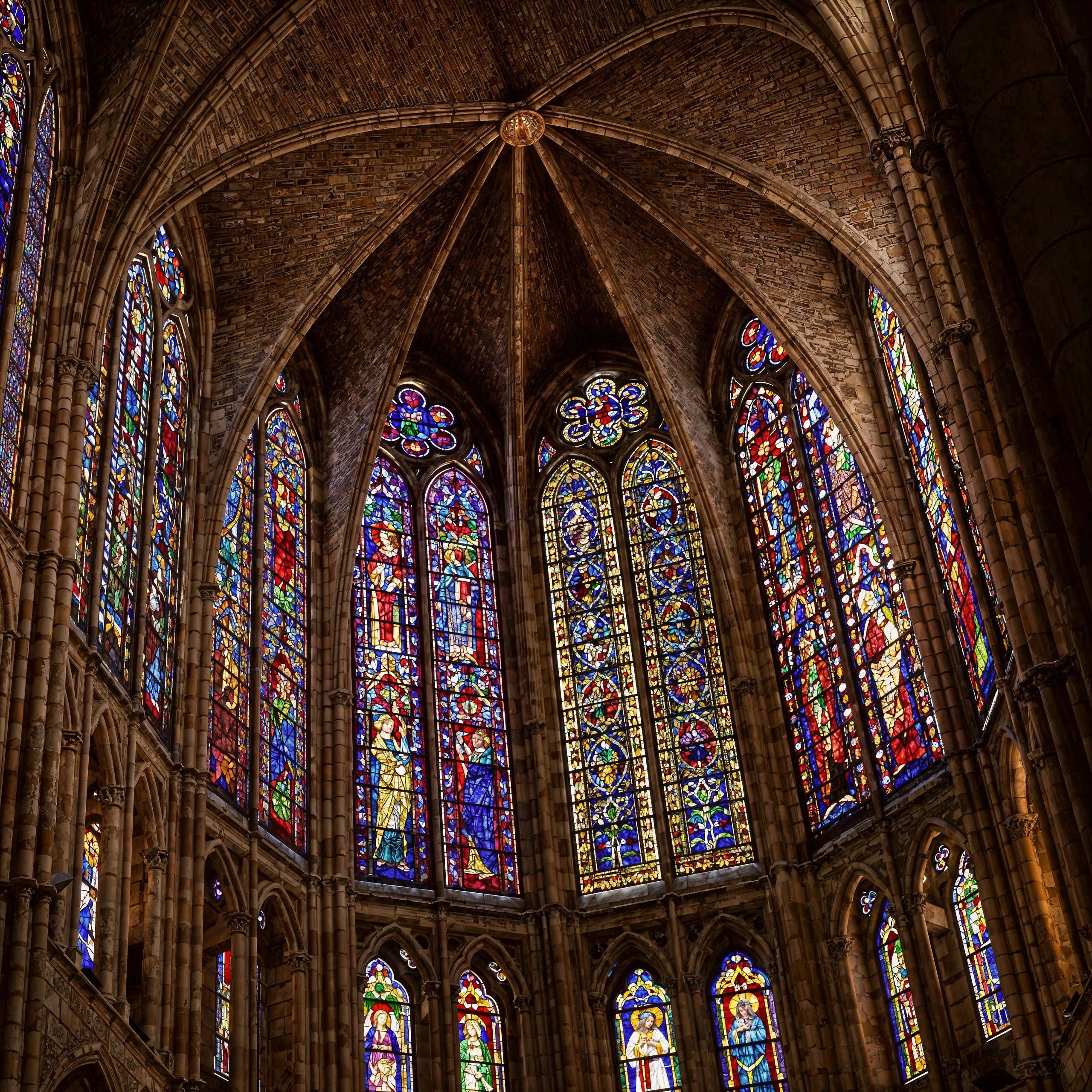 Majestic Gothic cathedral interior with towering stained-glass windows casting colorful light onto the stone walls after enhancement and upscaling